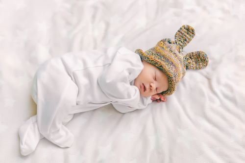 Nouveau-né endormi en pyjama blanc, coiffé d'un bonnet à oreilles de lapin